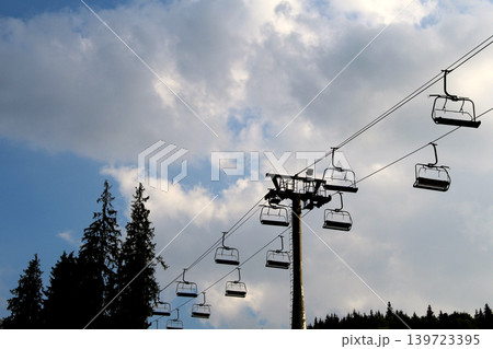 Silhouette of a chairlift over a forest on a mountain slope Silhouette of a chairlift over a forest on a mountain slope 139723395