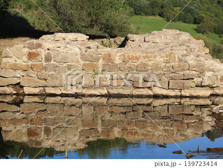 Ancient pillar of a stone bridge across a river in a mountainous area Ancient pillar of a stone bridge across a river in a mountainous area 139723414