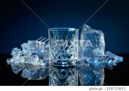 Crystal glass of vodka and ice shards against a black reflective background. 139723611
