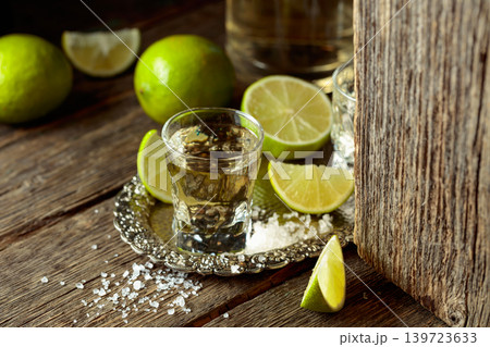 Tequila with salt and lime slices on a silver tray. Tequila with salt and lime slices on a silver tray. 139723633