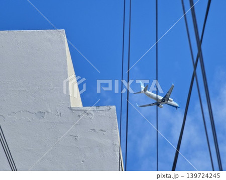 Jet aircraft crossing cloudy sky above utility cables in Cofico district Cordoba 139724245