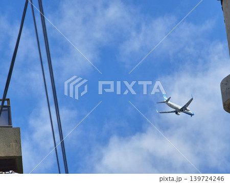 Airliner passing above concrete rooftop and dramatic clouds in Cordoba Argentina 139724246