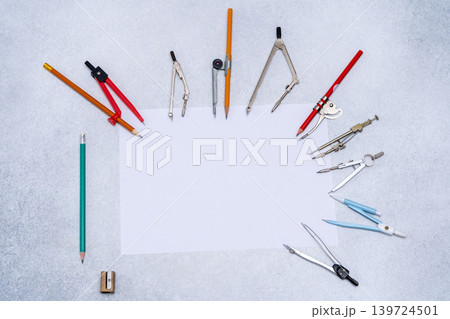 Drawing compass Tools Supplies arranged around Paper copy space. Stationery for school or engineering table top view Drawing compass Tools Supplies arranged around Paper copy space. Stationery for school or engineering table top view 139724501