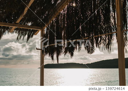 Gazebo made of palm leaves on the seashore at sunset. 139724614