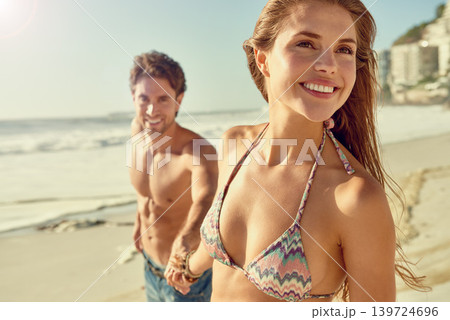 Travel, smile and couple holding hands while walking at a beach with love, adventure or bonding in nature. Happy, care or people at sea for summer, date or romantic journey with support, fun or trust 139724696