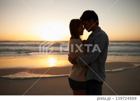 Couple, sunset and hugging on beach vacation, love and bonding on trip to ocean at dusk. People, embrace and romance on outdoor adventure at sea, peaceful environment and commitment in marriage 139724889