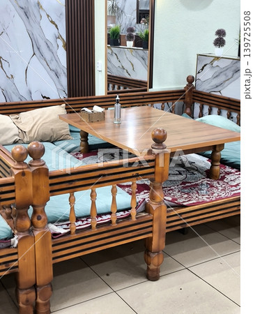 Traditional oriental daybed with a wooden table and cushions 139725508