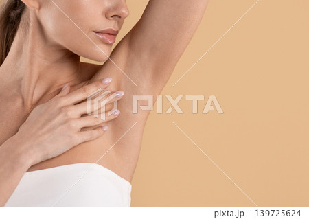 Young woman raising arm to show smooth clean underarm skin Young woman raising arm to show smooth clean underarm skin 139725624