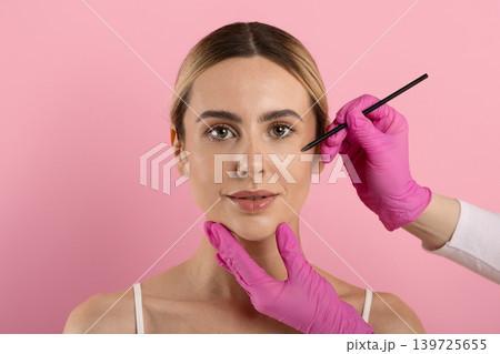 Doctor marking face of young woman with pencil before cosmetic procedure 139725655