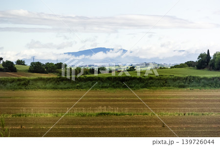 Wide grassy landscape next to the road and with a mountain landscape under an impressive sky 139726044