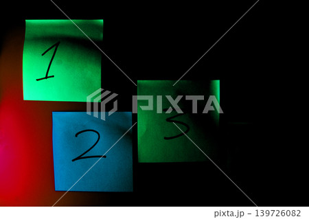 Three numbered sticky notes glowing in the dark with the notes are arranged Three numbered sticky notes glowing in the dark with the notes are arranged 139726082