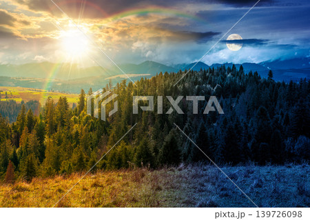 day meet night. mountain landscape on autumn equinox. sun and moon over green nature of carpathian mountains with fir forest. view of a scenery with rolling hills under epic sky. pasture near woods day meet night. mountain landscape on autumn equinox. sun and moon over green nature of carpathian mountains with fir forest. view of a scenery with rolling hills under epic sky. pasture near woods 139726098