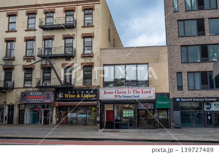New york, usa august 18,2024. Harlem street showing diverse architecture, fire escapes, and storefronts like an african restaurant, liquor store, and church New york, usa august 18,2024. Harlem street showing diverse architecture, fire escapes, and storefronts like an african restaurant, liquor store, and church 139727489
