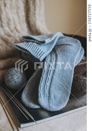Hand knitted socks with needles and yarn ball in a basket. Concept for handmade and hygge slow life. Hand knitted socks with needles and yarn ball in a basket. Concept for handmade and hygge slow life. 139727559