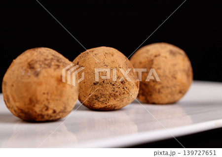 Beautiful candy truffle on a white plate on a black background Beautiful candy truffle on a white plate on a black background 139727651