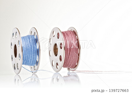 spools of blue and pink thread on a white background spools of blue and pink thread on a white background 139727663