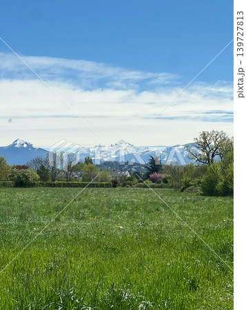 Snow-capped mountains rise majestically in the background over a lush green Snow-capped mountains rise majestically in the background over a lush green 139727813