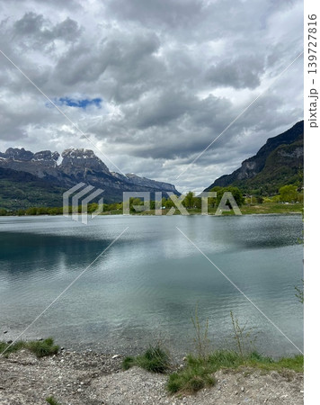 Scenic view of tranquil lake surrounded by lush green hills and majestic Scenic view of tranquil lake surrounded by lush green hills and majestic 139727816