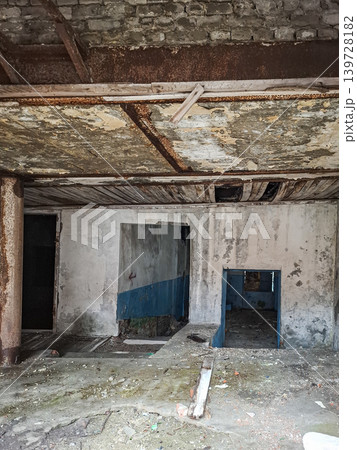 Inside of an abandoned building, concrete floors show decay, walls have peeling paint, and doorways remain empty and dark. This scene captures neglect and time gone by. Inside of an abandoned building, concrete floors show decay, walls have peeling paint, and doorways remain empty and dark. This scene captures neglect and time gone by. 139728182