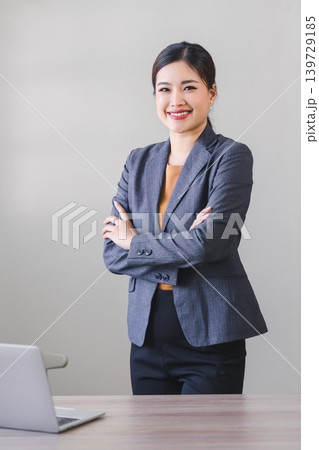 Confident asian businesswoman with friendly smile stands with arms crossed isolated on white background 139729185