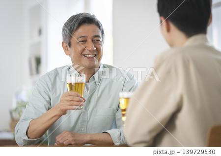 向かい合ってビールで乾杯をする2人の男性 向かい合ってビールで乾杯をする2人の男性 139729530