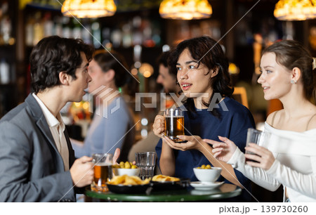Group of happy friends in bar, drinking beer and having conversation Group of happy friends in bar, drinking beer and having conversation 139730260