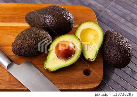 Whole and halved avocados on wooden cutting board Whole and halved avocados on wooden cutting board 139730298