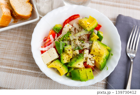 Salad of fresh tomatoes, avocado, onion and soft cheese 139730412