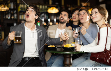 Fans watching match at a sports bar, cheering with drinks, energetic atmosphere, friendship and fun, people enjoying game together indoors 139730518