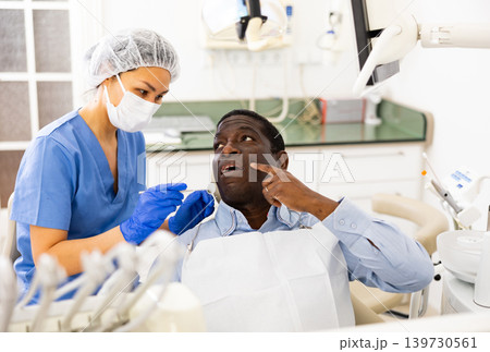 Patient pointing at tooth with problem during consultation in dental clinic Patient pointing at tooth with problem during consultation in dental clinic 139730561