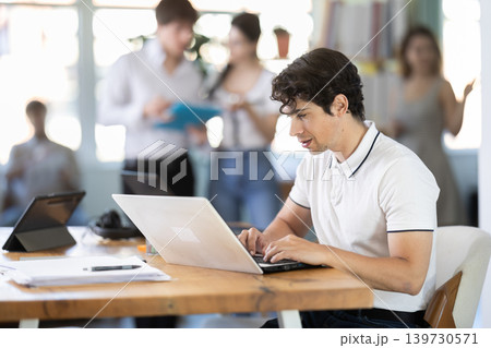 Young man working on laptop in modern office Young man working on laptop in modern office 139730571