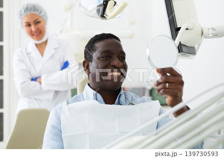 African american patient checks cured teeth with mirror African american patient checks cured teeth with mirror 139730593