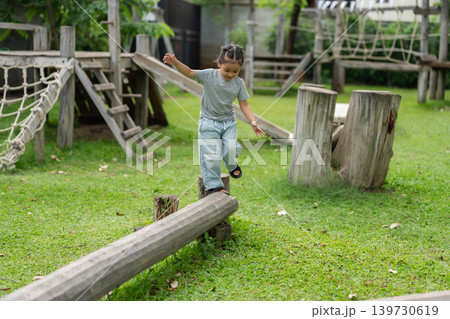 preschool child girl walking and balancing on wooden beam in outdoor Playground preschool child girl walking and balancing on wooden beam in outdoor Playground 139730619