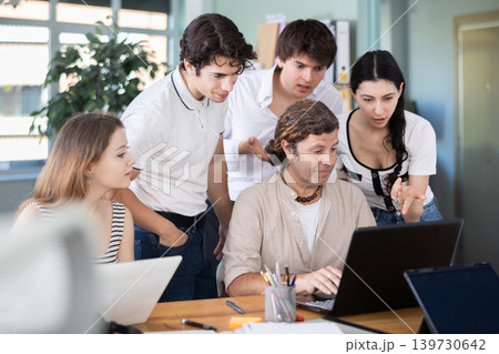 Colleagues looking at one laptop together in office Colleagues looking at one laptop together in office 139730642