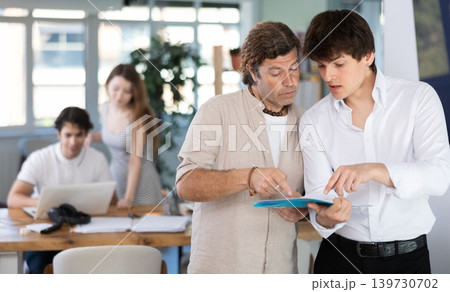 Two men colleagues discussing document 139730702