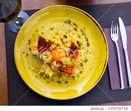 scrambled eggs with potatoes and ham, served on yellow plate 139730718