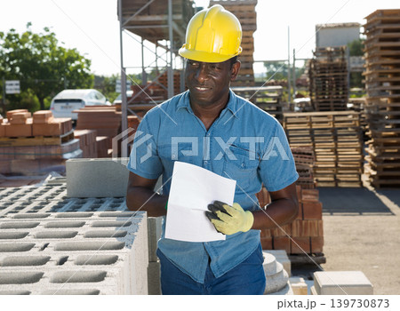 Man worker controlling quantity of bricks at hardware store Man worker controlling quantity of bricks at hardware store 139730873