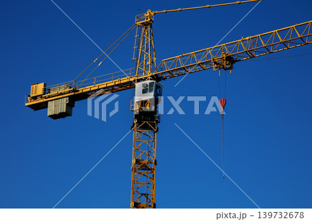 Yellow tower crane against clear blue sky at construction site Yellow tower crane against clear blue sky at construction site 139732678