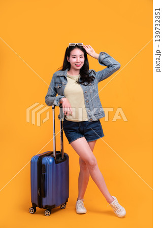 Happy Asian woman traveler standing and holding suitcase isolated on yellow background, Tourist girl having cheerful holiday trip concept, Full body composition. Happy Asian woman traveler standing and holding suitcase isolated on yellow background, Tourist girl having cheerful holiday trip concept, Full body composition. 139732851