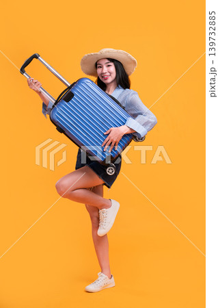 Happy Asian woman traveler standing and holding suitcase isolated on yellow background, Tourist girl having cheerful holiday trip concept, Full body composition. Happy Asian woman traveler standing and holding suitcase isolated on yellow background, Tourist girl having cheerful holiday trip concept, Full body composition. 139732885