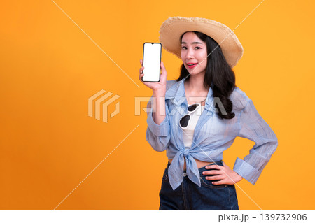 Happy Asian woman woman tourist holding a blank phone isolated on yellow background. 139732906