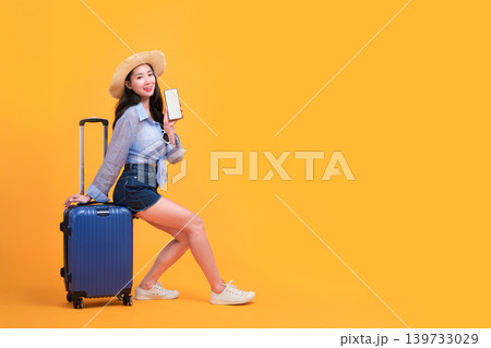 Happy Asian woman traveler standing and holding suitcase isolated on yellow background, Tourist girl having cheerful holiday trip concept, Full body composition. Happy Asian woman traveler standing and holding suitcase isolated on yellow background, Tourist girl having cheerful holiday trip concept, Full body composition. 139733029