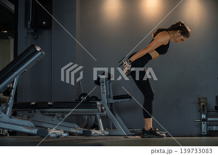Fitness asian woman doing exercise and lifting dumbbells weights at sport gym. 139733083