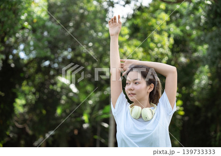 Young Asian woman doing stretches before exercising or training in a park before training, enjoying a healthy lifestyle. 139733333