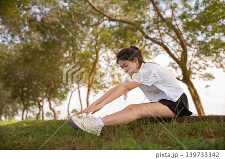 Young Asian woman doing stretches before exercising or training in a park before training, enjoying a healthy lifestyle. Young Asian woman doing stretches before exercising or training in a park before training, enjoying a healthy lifestyle. 139733342