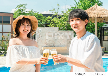 バカンス・リゾートホテルのプールサイドでビールグラスで乾杯するカップル バカンス・リゾートホテルのプールサイドでビールグラスで乾杯するカップル 139734372