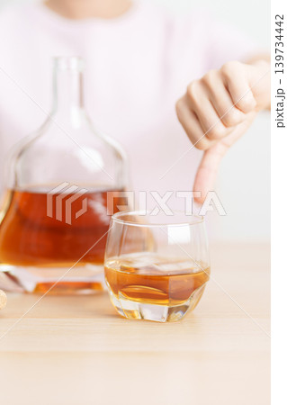 woman show thumb down hand gesture to refuse a glass of Cognac, Healthy man say no to alcohol drink, stop alcoholism and addiction concept. Responsible man reject a drink before driving and quit booze 139734442
