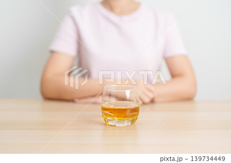 woman with glass of whiskey on table, suffering from alcohol addiction and alcoholism concept. depicting emotional distress, depression, substance abuse problem, unhealthy lifestyle and mental health woman with glass of whiskey on table, suffering from alcohol addiction and alcoholism concept. depicting emotional distress, depression, substance abuse problem, unhealthy lifestyle and mental health 139734449
