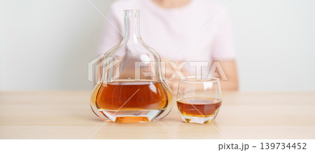 woman with glass of cognac on table, suffering from alcohol addiction and alcoholism concept. depicting emotional distress, depression, substance abuse problem, unhealthy lifestyle and mental health 139734452