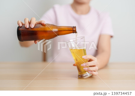 woman pour Beer into a glass on table, suffering from alcohol addiction, alcoholism concept. depicting emotional distress, depression, substance abuse problem, unhealthy lifestyle and mental health 139734457